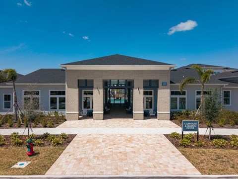 A building with a brick walkway in front of it and a sign that says "Clubhouse".