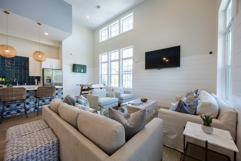 A living room with a large couch and a flat screen TV mounted on the wall.