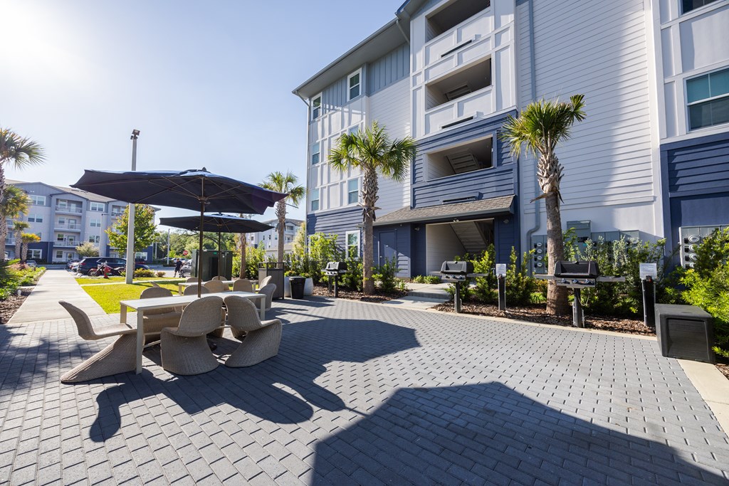 A sunny day at a modern outdoor seating area with a black umbrella and a bench.