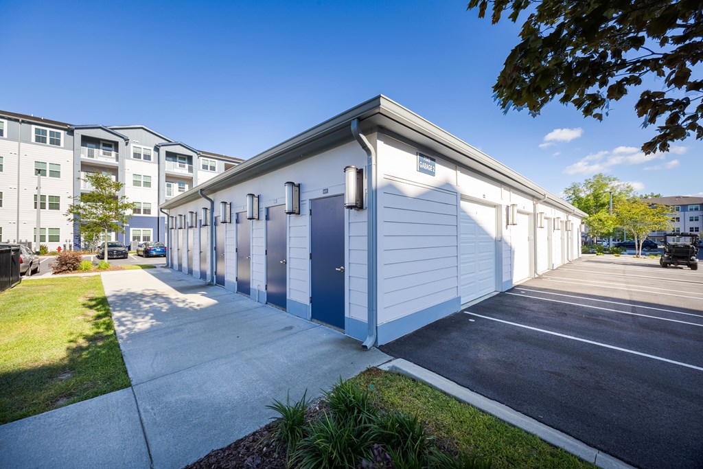 A white building with a blue door is surrounded by a parking lot.