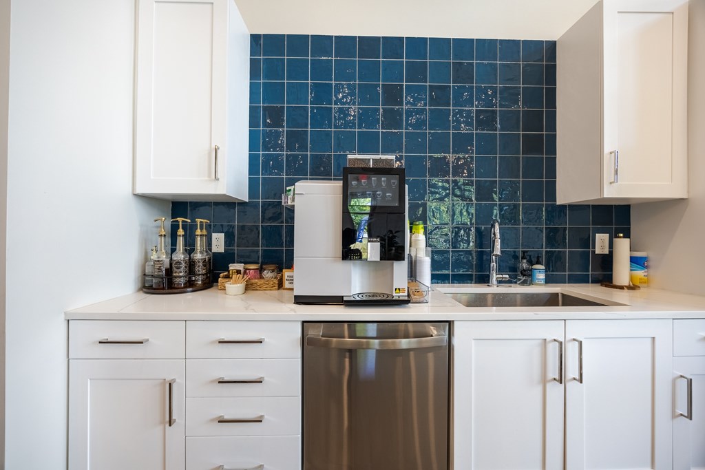 A kitchen with a stainless steel dishwasher and white cabinets.