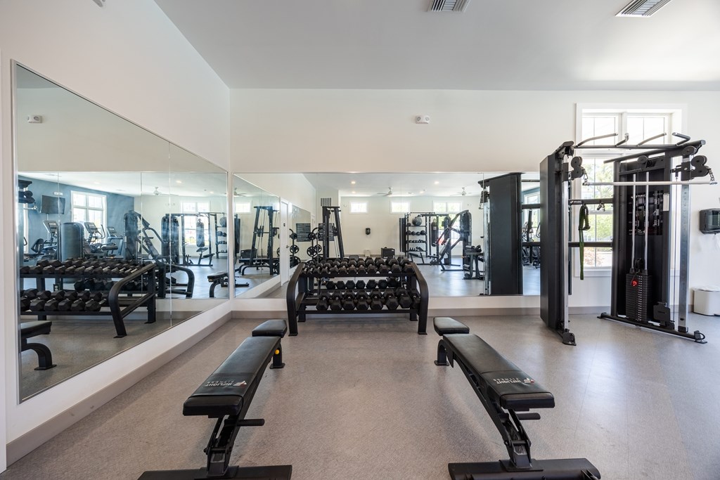 A gym with a mirror on the wall and a bench in the middle.