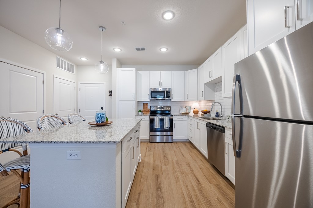 A modern kitchen with a stainless steel refrigerator and white cabinets.