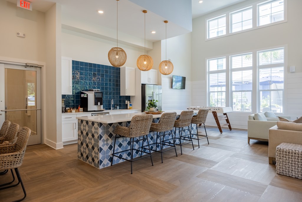 A kitchen with a blue tile backsplash and a bar area with chairs.