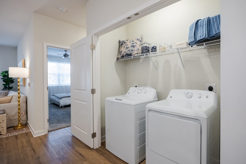A laundry room with two washing machines and a shelf with towels.