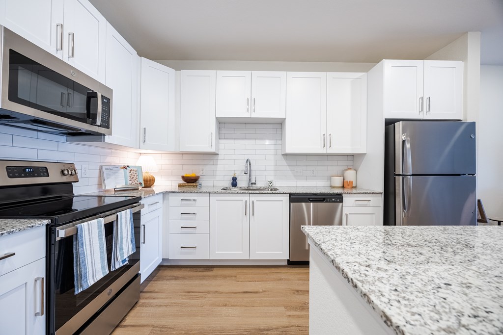 A kitchen with white cabinets and a granite countertop.