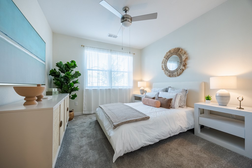 A bedroom with a bed, nightstand, and a plant.