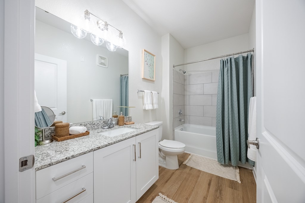 A white bathroom with a toilet, sink, and shower.