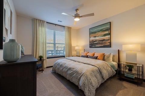 A bedroom with a large bed and a ceiling fan.