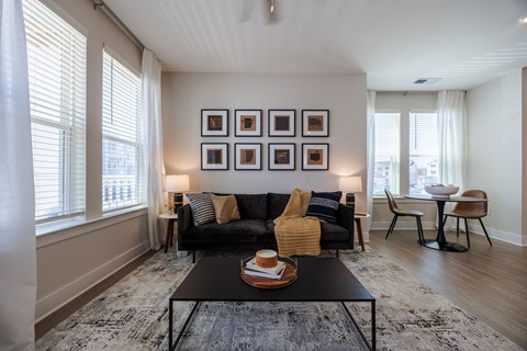 A living room with a black couch and a coffee table in the center.