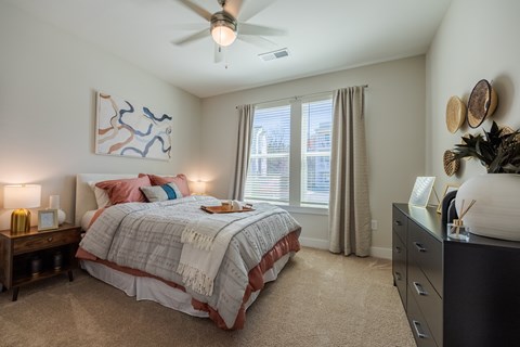 A bedroom with a bed, nightstand, and a ceiling fan.