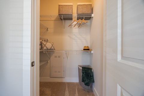 A hallway with a bench and a coat rack.