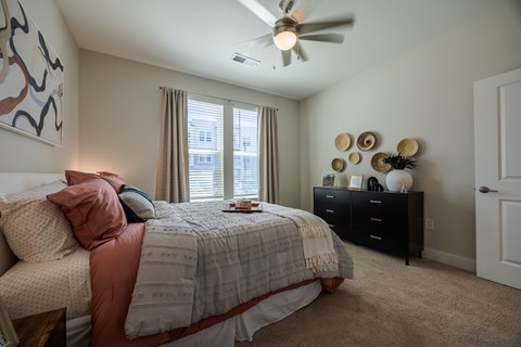 A bedroom with a bed, dresser, and ceiling fan.