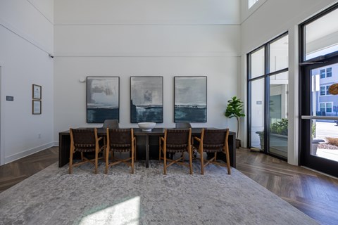 A dining room with a table and chairs and three pictures on the wall.