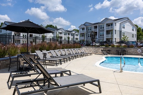 A pool area with sun loungers and a black umbrella.