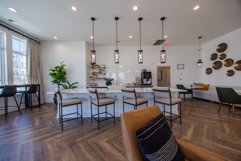 A modern living room with a wooden floor and a kitchen area in the background.