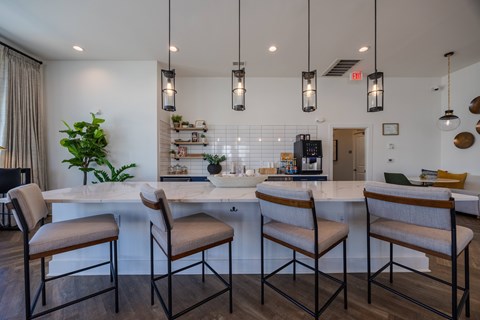 A kitchen with a white countertop and brown chairs.