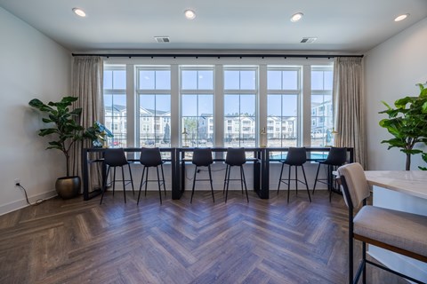 A conference room with a long table and chairs, a potted plant, and a view of buildings outside the window.