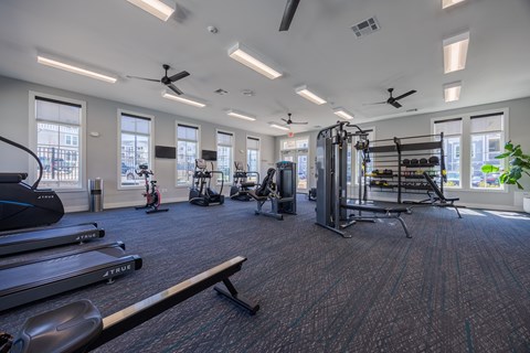A gym with a variety of equipment including treadmills, elliptical machines, and a weight rack.