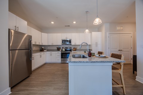 A kitchen with a stainless steel refrigerator and a marble countertop.