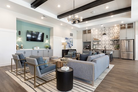 A modern living room with a grey sofa, a black and white striped rug, and a television on the wall.