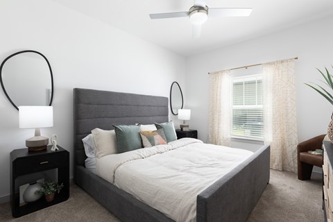 A bedroom with a large bed and a ceiling fan.
