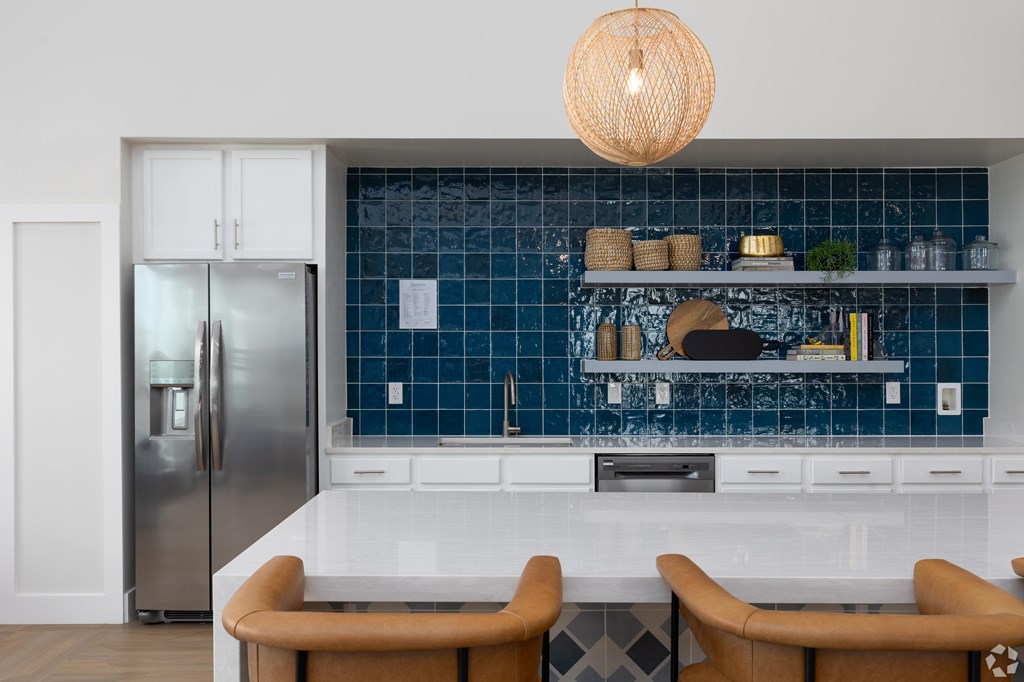A kitchen with a blue backsplash and a refrigerator.