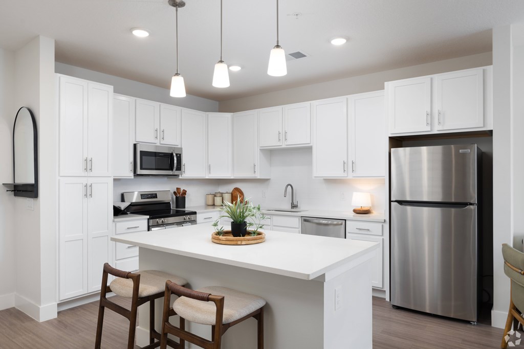 A modern kitchen with white cabinets and a stainless steel refrigerator.