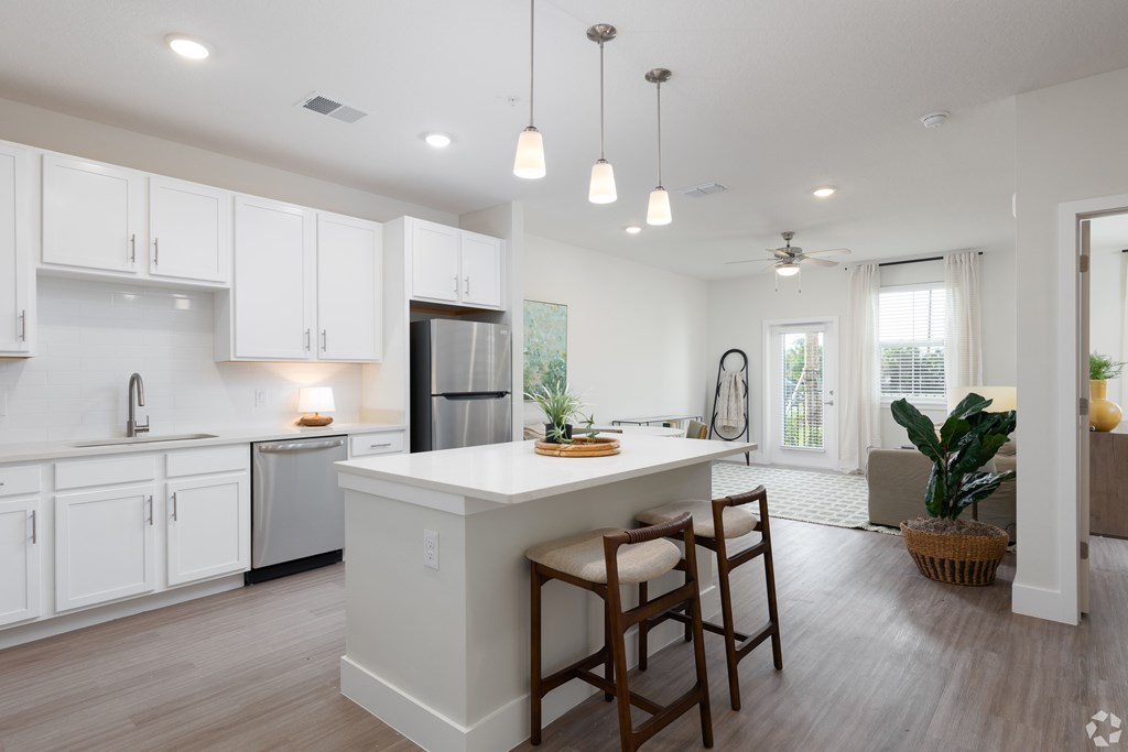 A kitchen with white cabinets and a large island with bar stools.