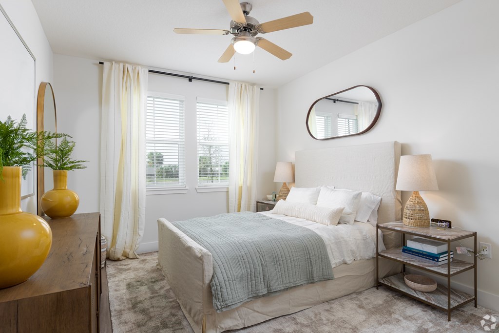 A bedroom with a bed, a ceiling fan, and a window with curtains.
