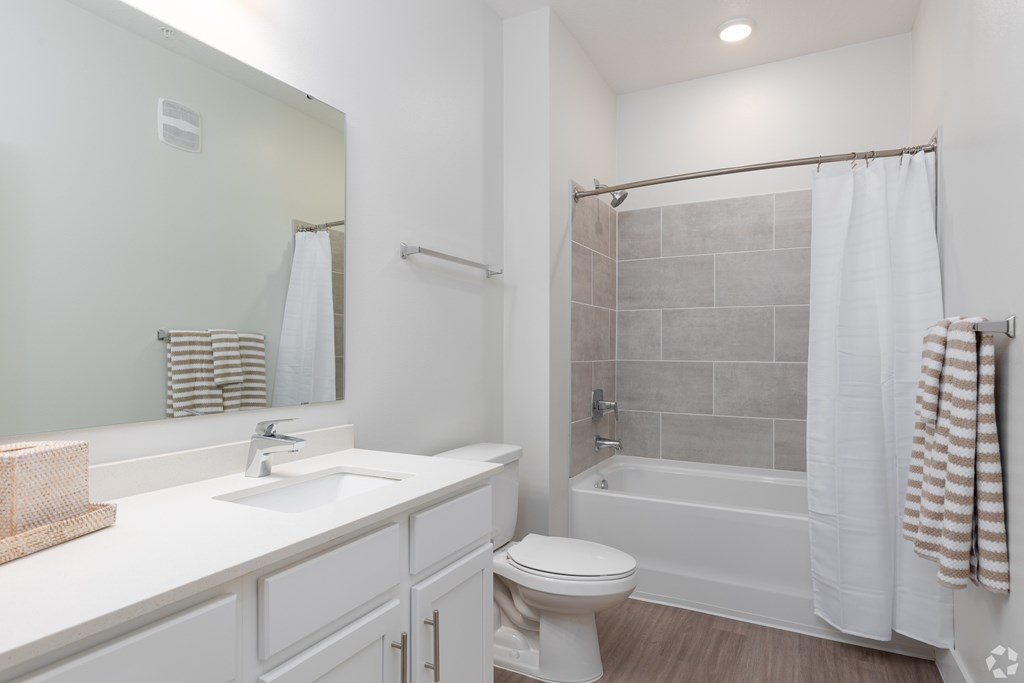 A white bathroom with a toilet, sink, and shower.