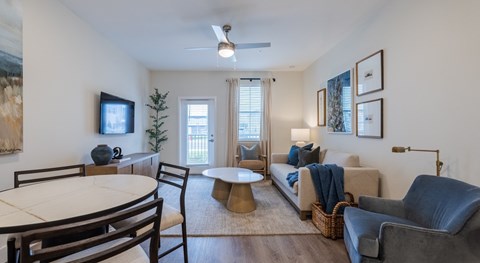 A living room with a white ceiling fan and a painting on the wall.