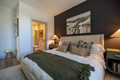 A bedroom with a large bed and a painting on the wall.