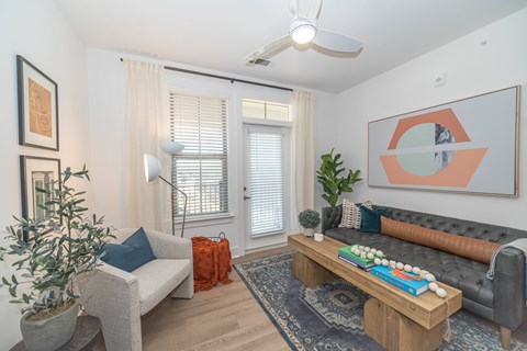 A living room with a grey couch, a wooden coffee table, and a painting on the wall.