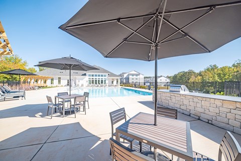 A large umbrella shades a table and chairs on a patio.