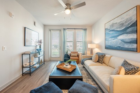 A living room with a white couch and a painting on the wall.