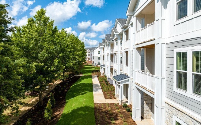 a row of white houses with grass and trees