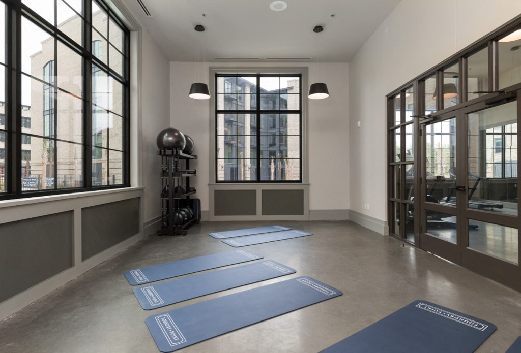 a yoga room with yoga mats on the floor and large windows