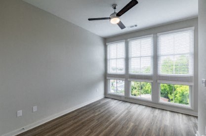 A room with a ceiling fan and a window with blinds.