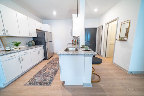 a kitchen with white cabinets and a blue counter top and a black refrigerator