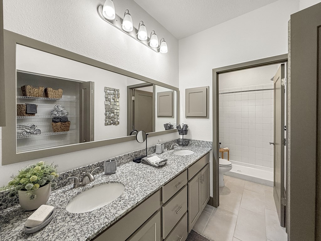 A bathroom with a granite countertop and a large mirror above the sink.