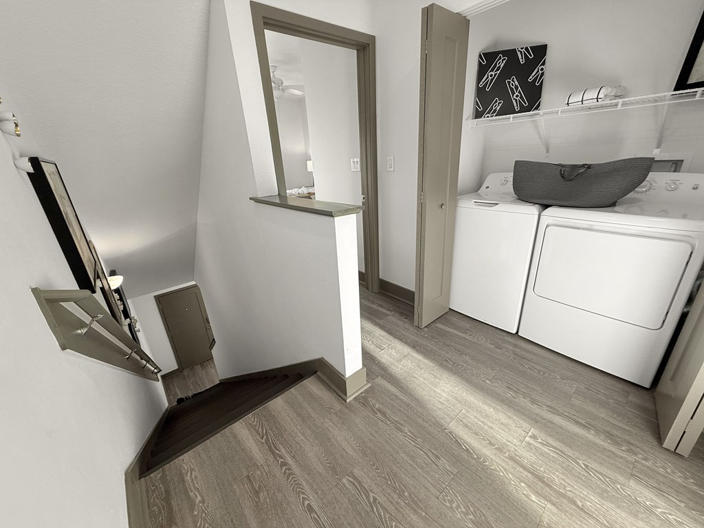 A bathroom with a washing machine and a mirror.