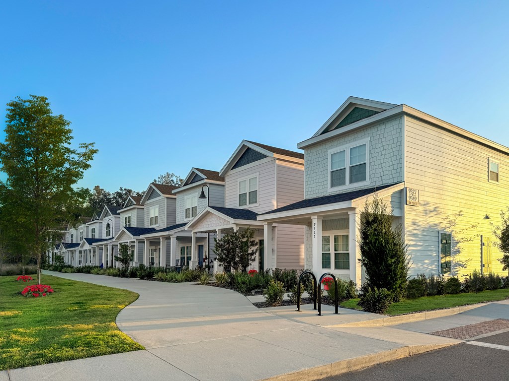 A row of houses with a sidewalk in front of them.