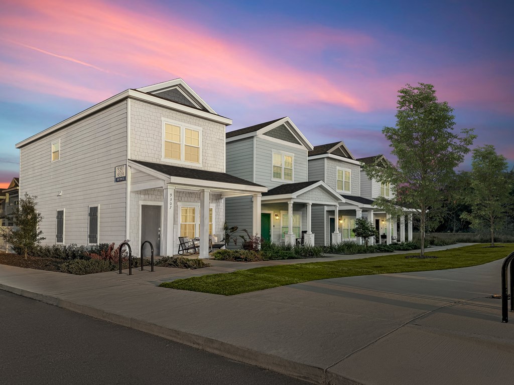 A row of houses with a sidewalk in front.