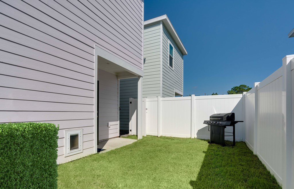 A white house with a grey roof and a white fence.