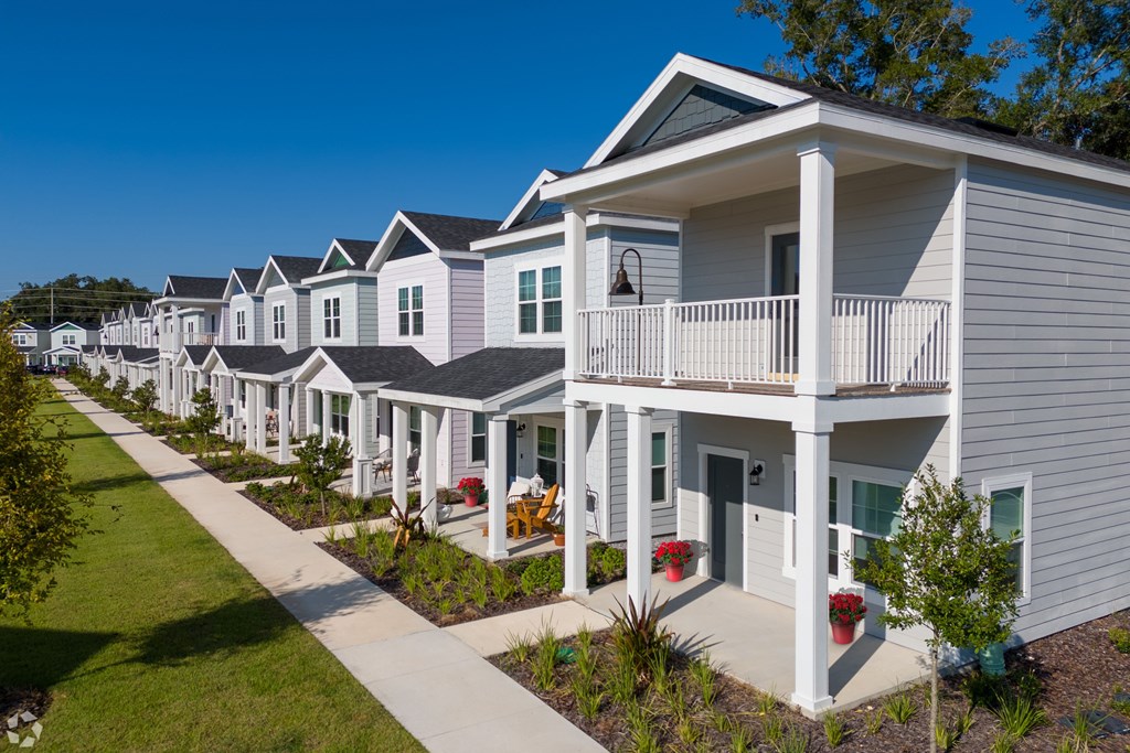 A row of houses with white siding and red flower pots.