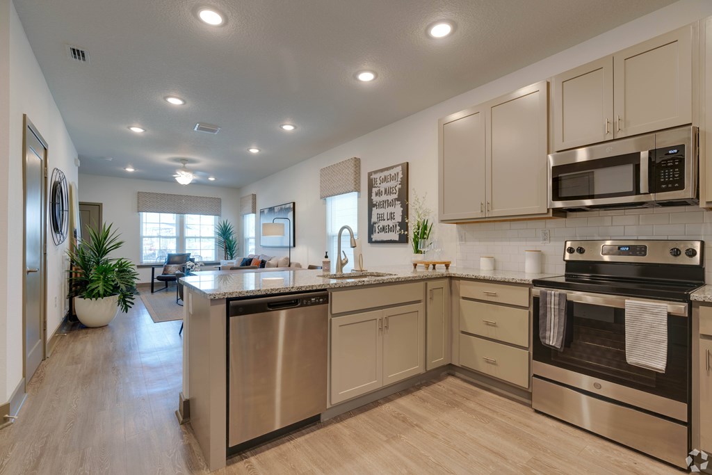 A modern kitchen with stainless steel appliances and wooden floors.