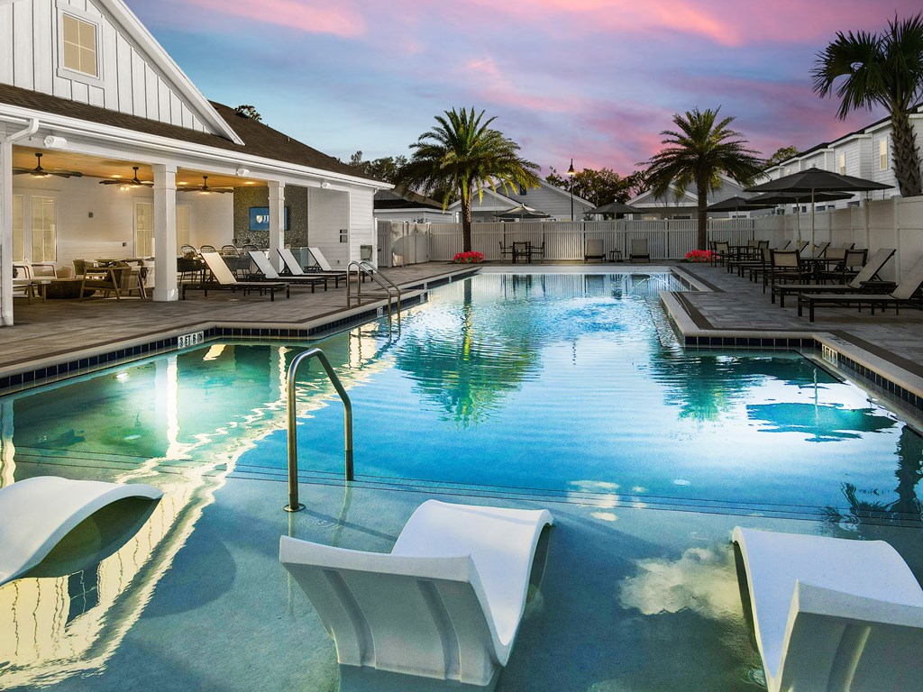 A pool with a slide and lounge chairs.