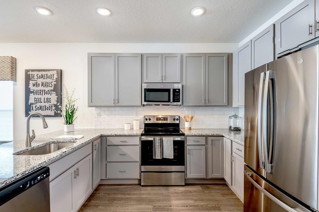 A kitchen with a refrigerator, sink, and stove.