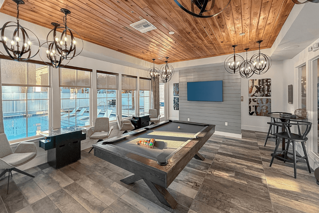 A billiard table is in the middle of a room with a wooden ceiling.